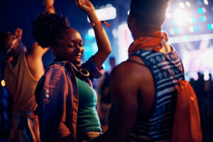Carefree African American couple dancing and having fun on summer music festival at night.